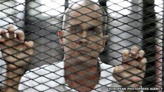 Australian journalist Peter Greste stands inside a cage in a Cairo court
