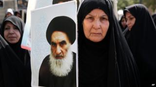 An Iraqi woman living in Iran holds a poster of the Grand Ayatollah Ali al-Sistani during a protest