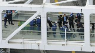 Investigators and firefighters work at the scene where a man has set himself on fire, on a pedestrian walkway at Tokyo's busy Shinjuku railway station, Sunday, June 29