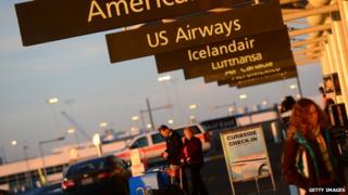 American Airlines and US Airways signs stand next to each others at Denver International Airport in Denver 9 December 2013