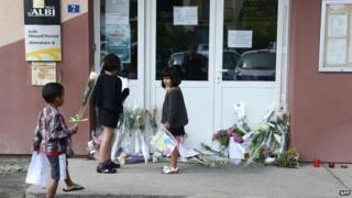 Children leave flowers in front of the school
