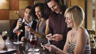 A group of people at a bar using their smartphones.