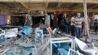 Civilians inspect the site of a bomb attack in the Jihad neighbourhood in Baghdad, 19 July 2014