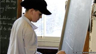 A schoolboy in Victorian clothes at a blackboard