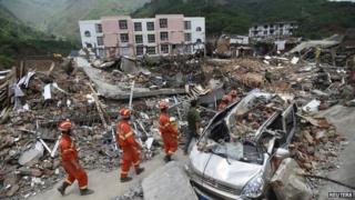 Rescue workers walk past debris of houses at an earthquake zone in Ludian county, Zhaotong, Yunnan province, on 5 August 2014