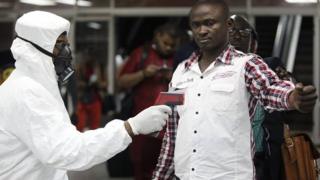 Nigerian port health official uses thermometer on worker at arrivals hall of airport in Lagos, Nigeria. 6 Aug 2014
