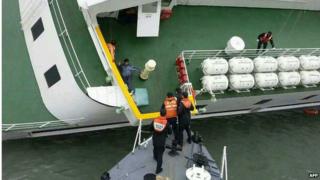 Coast guard officers rescue passengers from the deck of the Sewol