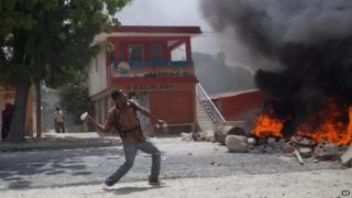A supporter of Haiti's former President Jean-Bertrand Aristide throws rocks in Port-au-Prince, August 14, 2014.