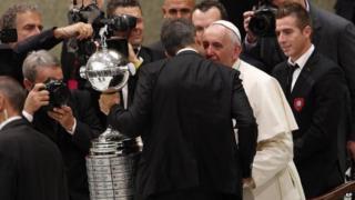 Pope Francis greets San Lorenzo football team players holding the Copa Libertadores they won last week at the Vatican on 20 August, 2014