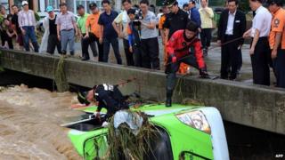In a photo taken on 25 August, 2014, South Korean rescue workers attempt to secure a bus submerged by floodwaters in the south-eastern town of Changwon