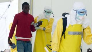 Health workers, wearing Personal Protective Equipment, arrive with a potentially contaminated patient at Elwa hospital in Monrovia (7 September 2014)