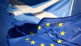 A European Union flag and Saltire flag blow in the wind near to Glen Coe, Scotland