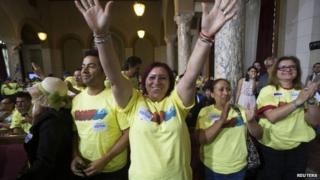 Hotel worker Blanca Aldana (C) cheers after a City Council vote to increase minimum wage at City Hall in Los Angeles, California 24 September 2014