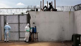 Health workers stand outside the Island Clinic Ebola isolation and treatment centre in Monrovia, Liberia, on 26 September