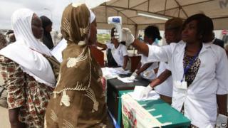 Нигерийский санитарный врач использует термометр для проверки мусульманских паломников на Эболу в лагере Хадж перед посадкой в ??самолет для Саудовской Аравии в международном аэропорту Муртала Мухаммед в Лагосе, Нигерия. Четверг, 18 сентября.