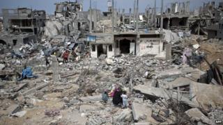 Palestinians walk amid destroyed buildings in al-Tufah, east of Gaza City, 11 October 2014