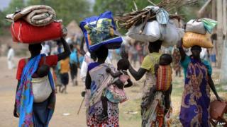 Displaced South Sudanese women carry their possessions