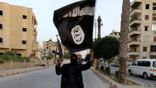 Islamic State militant waves flag in Raqqa, Iraq, on 29 June 2014
