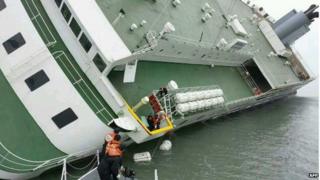 This South Korea Coast Guard handout photo taken at sea some 20 kilometres (12 miles) off the island of Byungpoong in Jindo on 16 April 2014 shows South Korea Coast Guard members rescuing some of the passengers and crew aboard a South Korean ferry sinking on its way to Jeju island from Incheon