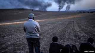 A Kurdish man prays as smokes rises from the town of Kobane, near the Turkish border with Syria.