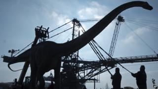 workers in Germany transport a model of a dinosaur at the exhibition "World of Dinosaurs" near Leipzig