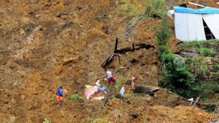 Sri Lankan residents search the site of a landslide caused by heavy monsoon rains in Koslanda village in central Sri Lanka on October 30, 2014.