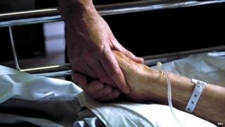 Nurse holding a patient's hand in hospital