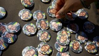 Badges showing the portraits of former South African president Nelson Mandela and current South African president Jacob Zuma with the logo of ruling African National Congress (ANC) party are sold during a march organised by the Congress of South African Trade Unions (Cosatu) to support the ruling ANC party in Durban, on 26 April 2014