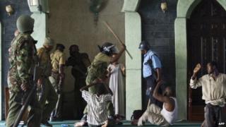 File photo: A police officer hits men as police storm the Masjid Musa Mosque and detain alleged jihadist radicals in the Majengo area of Mombasa, 2 February 2014