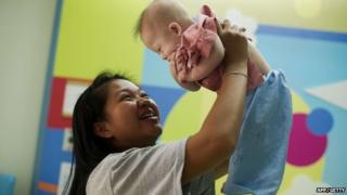 Thai surrogate mother Pattaramon Chanbua (L) holds her baby Gammy at the Samitivej hospital, Sriracha district in Chonburi province, Thailand on 4 August 2014