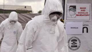Health workers wearing Ebola protective gear remove the body of a man that they suspect died from the Ebola virus in Liberia