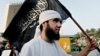 Сторонник «Ансар аш-шариата» в Ливии несет флаг группы, на котором написано: «Нет Бога, кроме Аллаха, и Мухаммед является его посланником».
