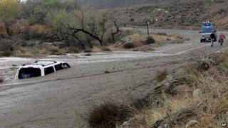 A television news crew walks away from a vehicle caught in an overnight mudslide on Soboba Road near Gilman Springs Road in San Jacinto, California 4 December 2014