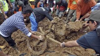 Villagers dig out a motorcycle buried in the mud after a landslide hit the village of Sampang in Banjarnegara, December 13, 2014