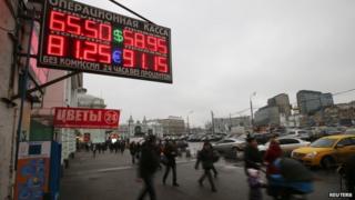 People walk past boards showing currency exchange rates in Moscow, December 17, 2014.