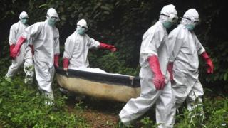 A burial team carry the body of an Ebola victim to a grave in Monrovia, Liberia - 18 October 2014