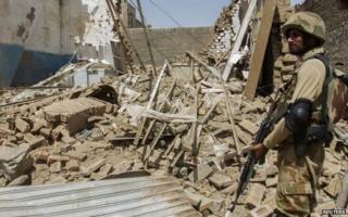 A Pakistani soldier stands near the debris of a house which was destroyed during a military operation against Taliban militants in the town of Miranshah in North Waziristan in 9 July 2014