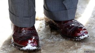 A close-up of a man's shoes in the snow