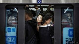 Chinese commuters crowd onto a subway car on the metro during rush hour on October 16, 2014 in Beijing,