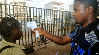 Guinean schoolgirl having temperature taken