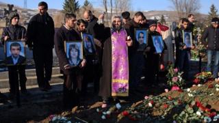 People hold portraits of six dead members of the Avetisyan family during a funeral in the city of Gyumri, Armenia