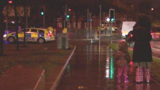 Woman in pyjamas with child at security alert scene