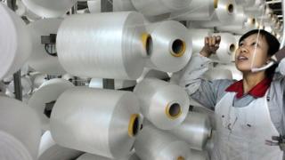 This picture taken on January 12, 2015 shows a Chinese worker checking a machine making blankets for exports at a factory in Yiwu, east China's Zhejiang province.