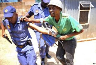 Police arrest a man suspected of looting a store in Soweto, South Africa on 22 January 2015