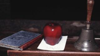Книга, яблоко и колокольчик на столе