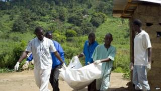 Guinean Red Cross workers carry the corpse of an Ebola victim in Patrice near Macenta on November 21, 2014