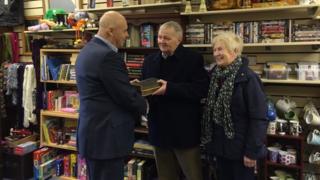 Brian a Heulwen Parry yn derbyn y Beibl gan John Donnelly o elusen Tŷ'r Eos