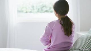 A girl sits alone on bed
