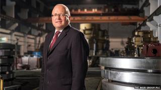 Keith Cochrane stands in a factory