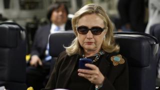 Former Secretary of State Hillary Rodham Clinton checks her Blackberry from a desk inside a C-17 military plane upon her departure from Malta, in the Mediterranean Sea, bound for Tripoli, Libya